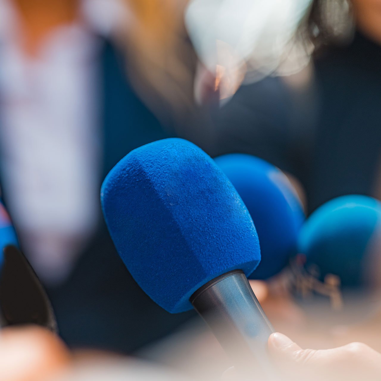 Eine Gruppe von Menschen hält Mikrofone vor einer Menschenmenge