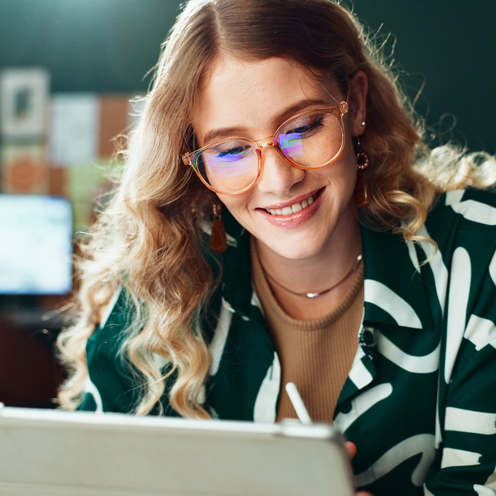Eine lächelnde Frau mit Brille nutzt ein Tablet
