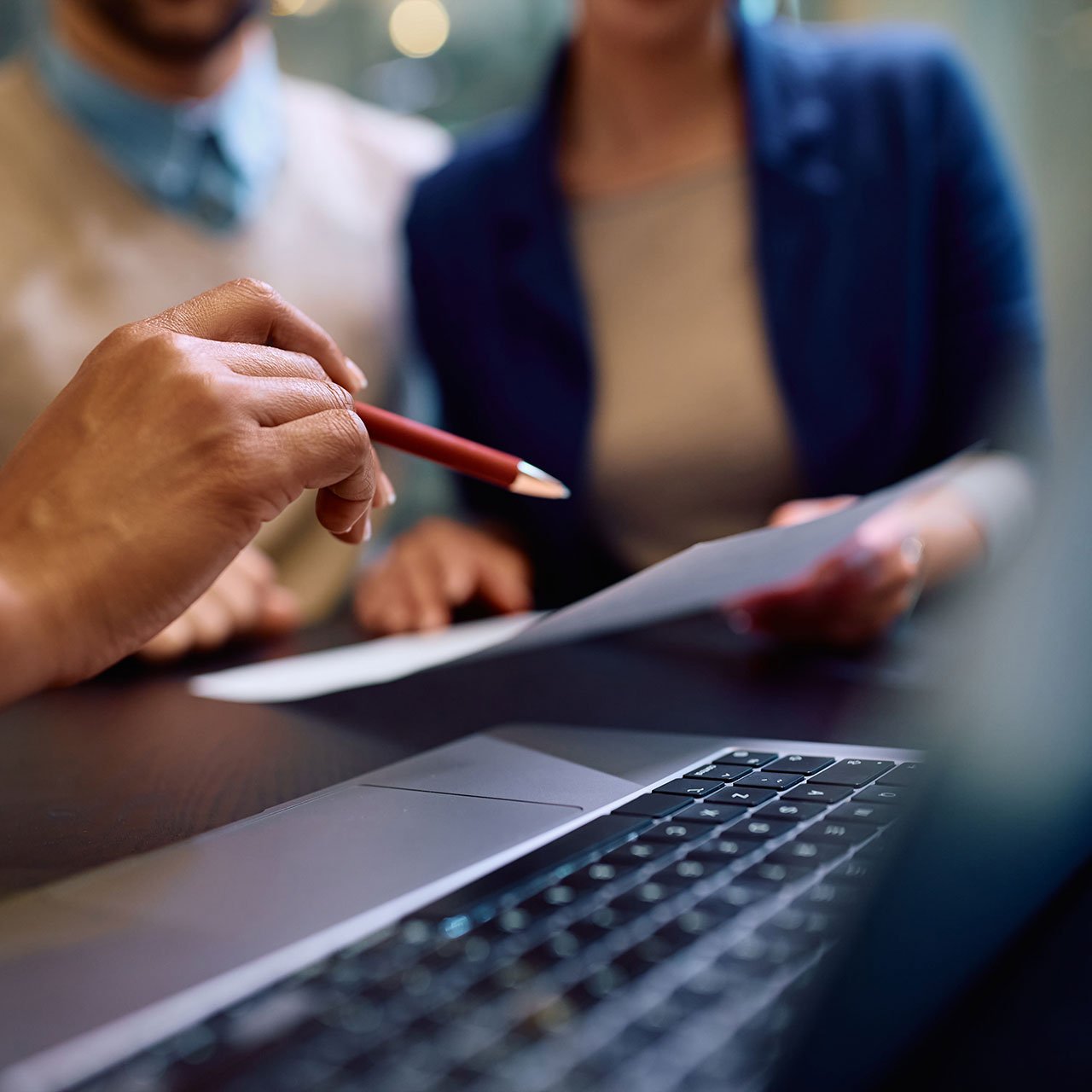 Mehrere Personen sitzen an einem Tisch und diskutieren Inhalte an einem Laptop