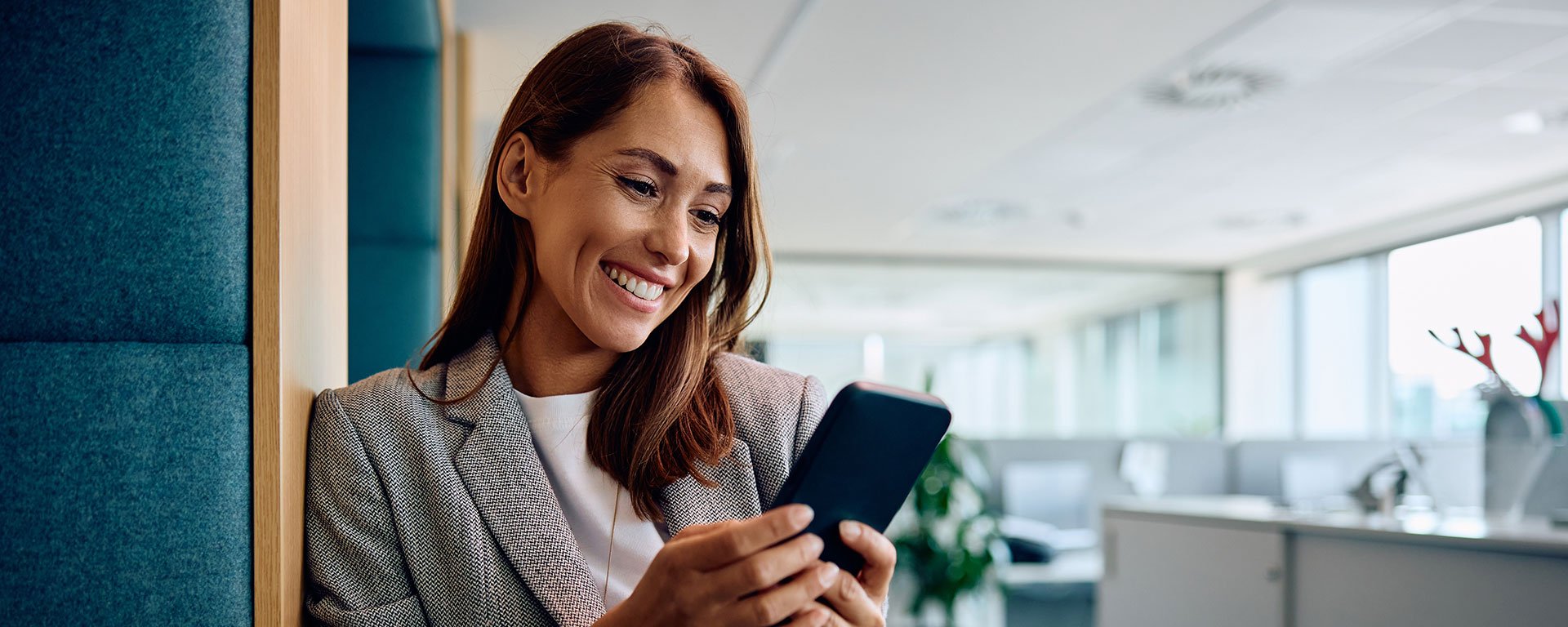 Eine Frau in einem Büro hält ihr Handy